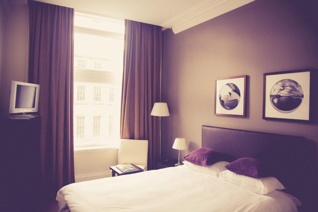 A hotel room with a bed, lamps, and pictures on the wall