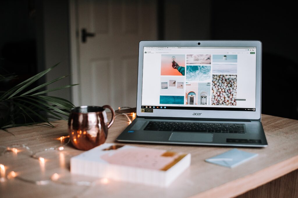 A laptop with a coffee mug, a book, and string lights on the table