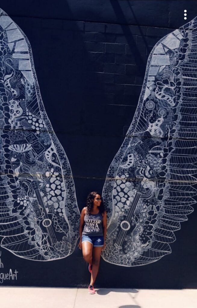 Brittney posing in front of angel wings street art in Nashville