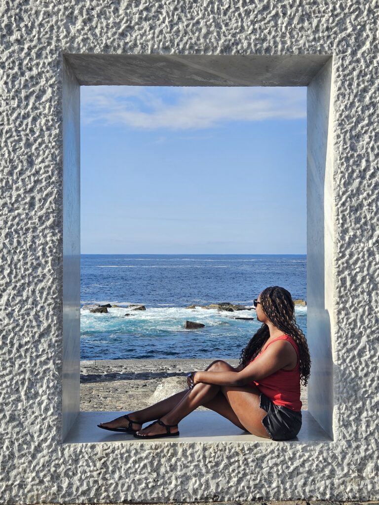 A woman sitting in a giant square overlooking the sea in Garachico
