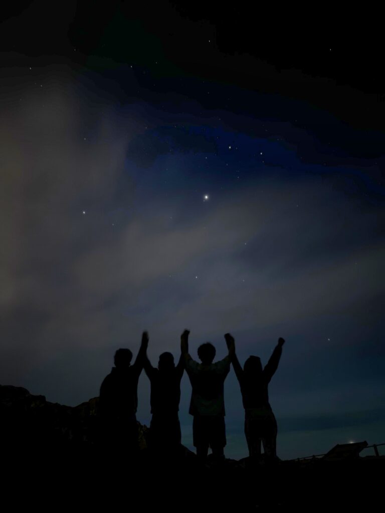 A silhouette of four friends holding hands under the starts at Mount Teide National Park