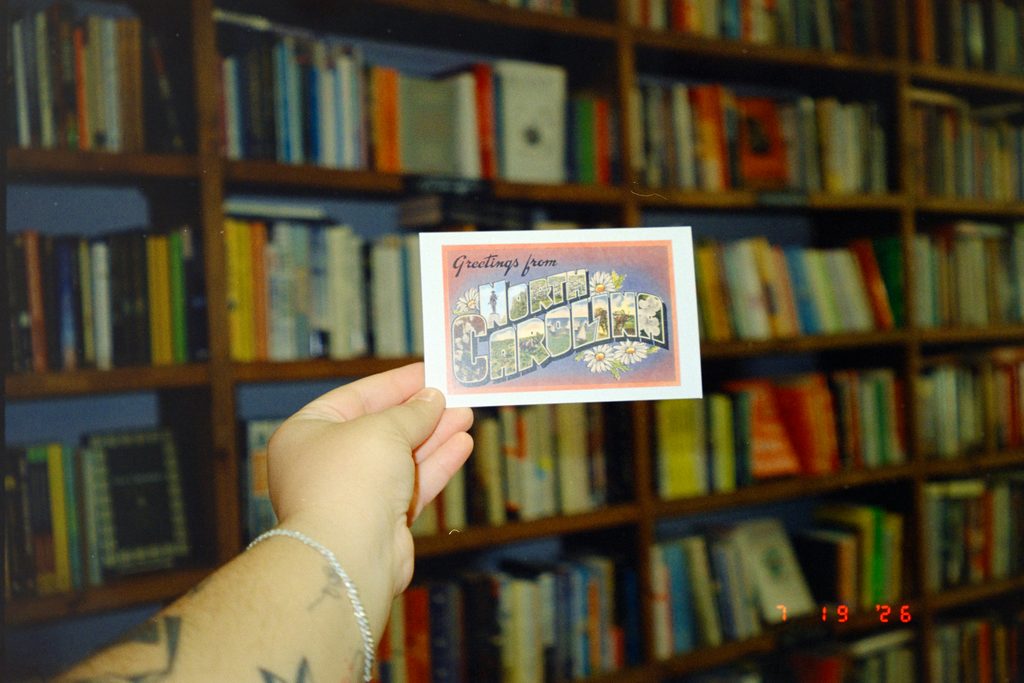 A hand holding a postcard for solo travel memories