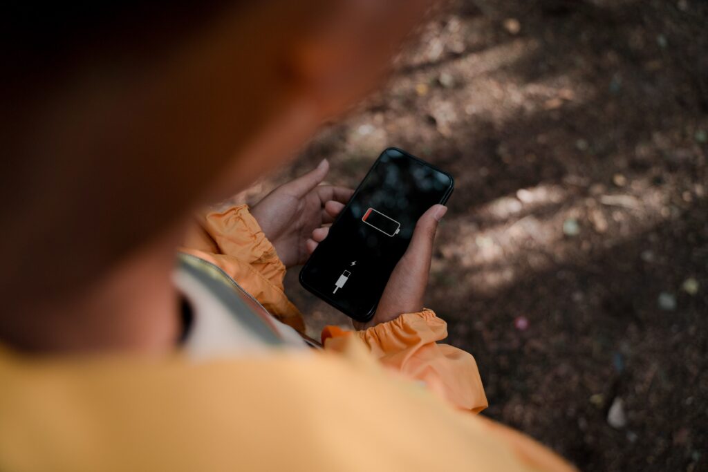 A person outdoors holding a phone with a low battery 